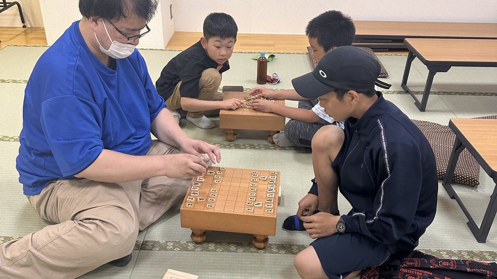 畳の部屋で将棋を指す獣王の大人と子どもたち